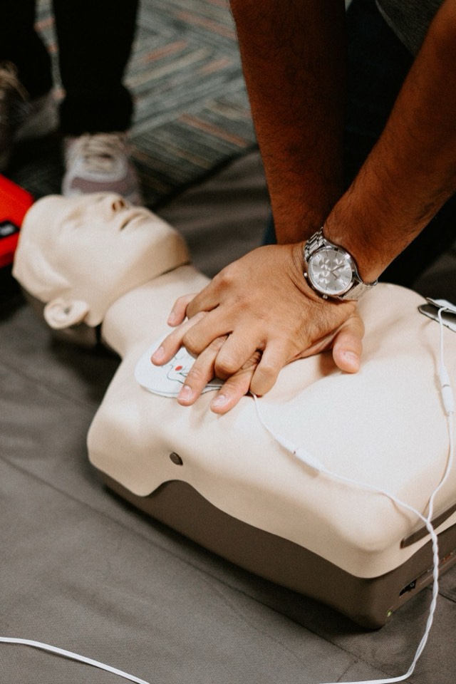 Close-up of hands performing chest compressions on a training manikin